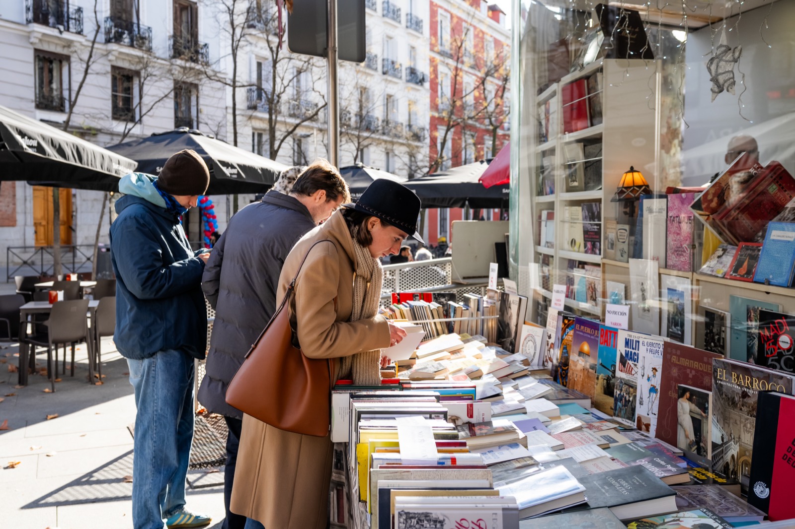 People browsing an open-air second-hand book stall on a sunny Madrid street